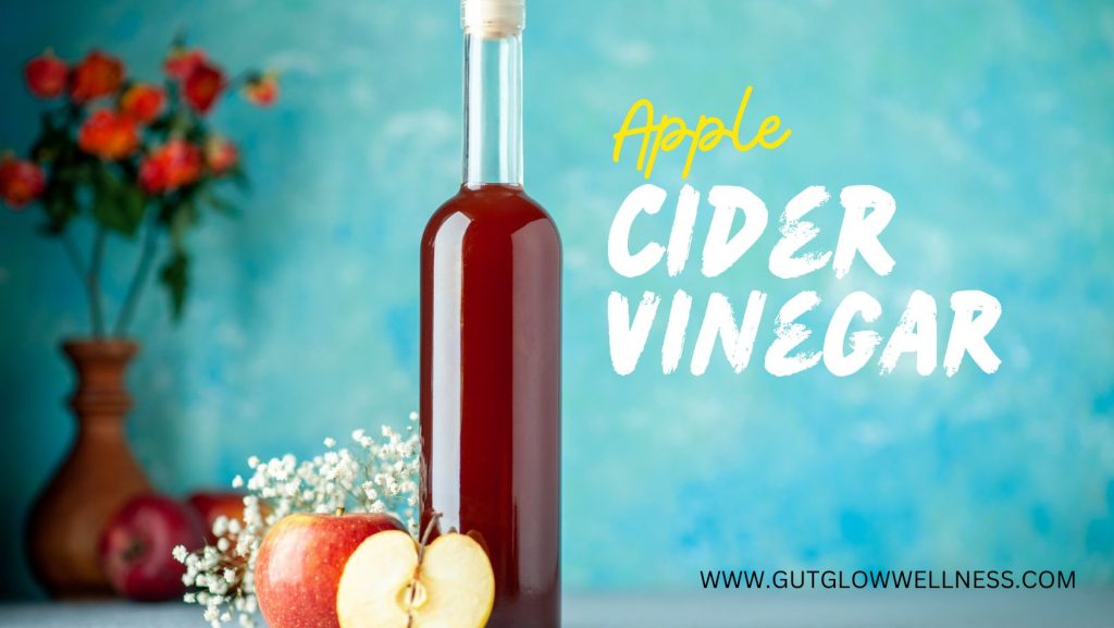 Apple cider vinegar in a glass with ingredients for gut health like ginger, honey, and lemon.